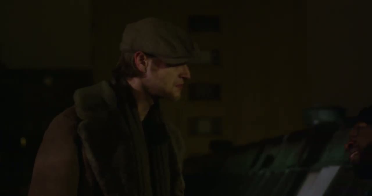 A man in a flat cap during a tense scene from KOPC Origins