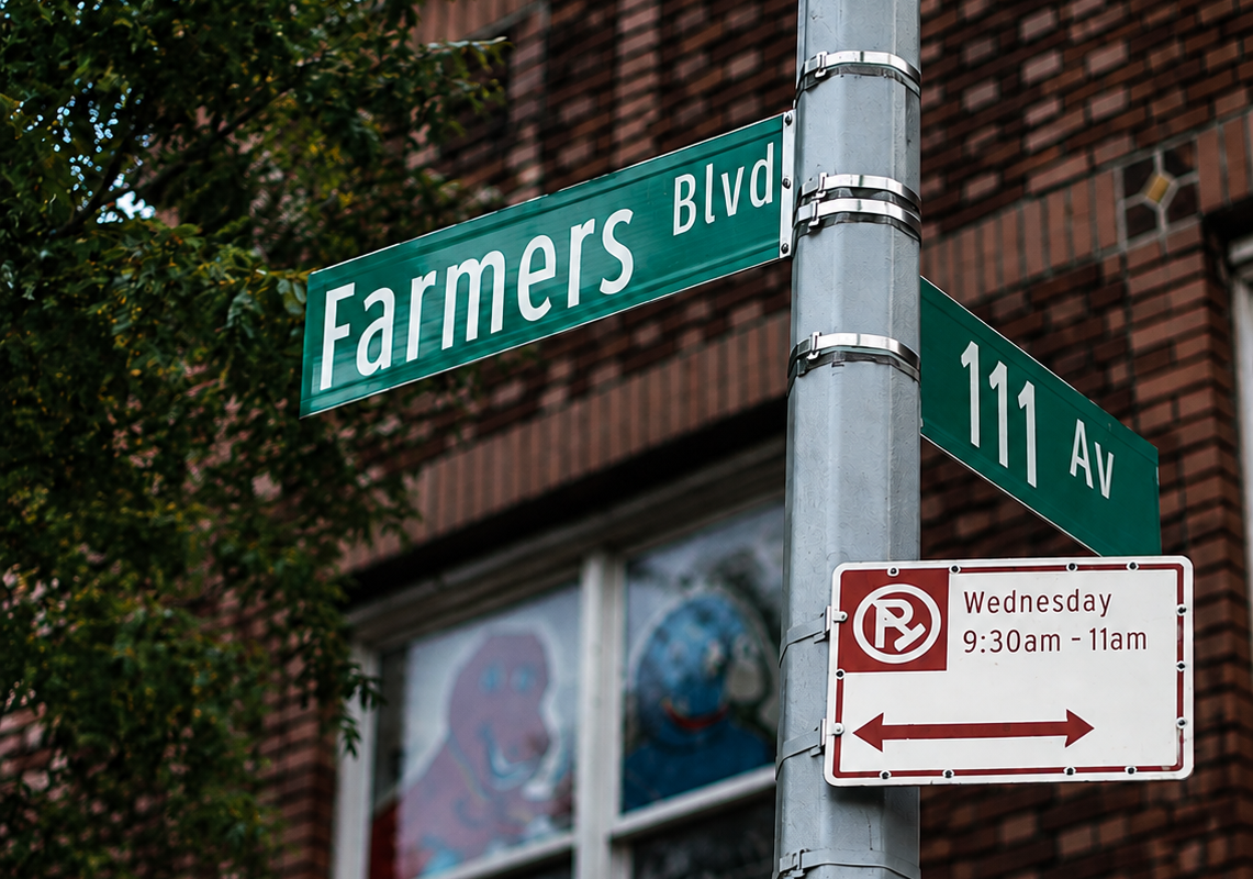 Farmers Boulevard and 111 Avenue street signs with an orange-hand pedestrian signal